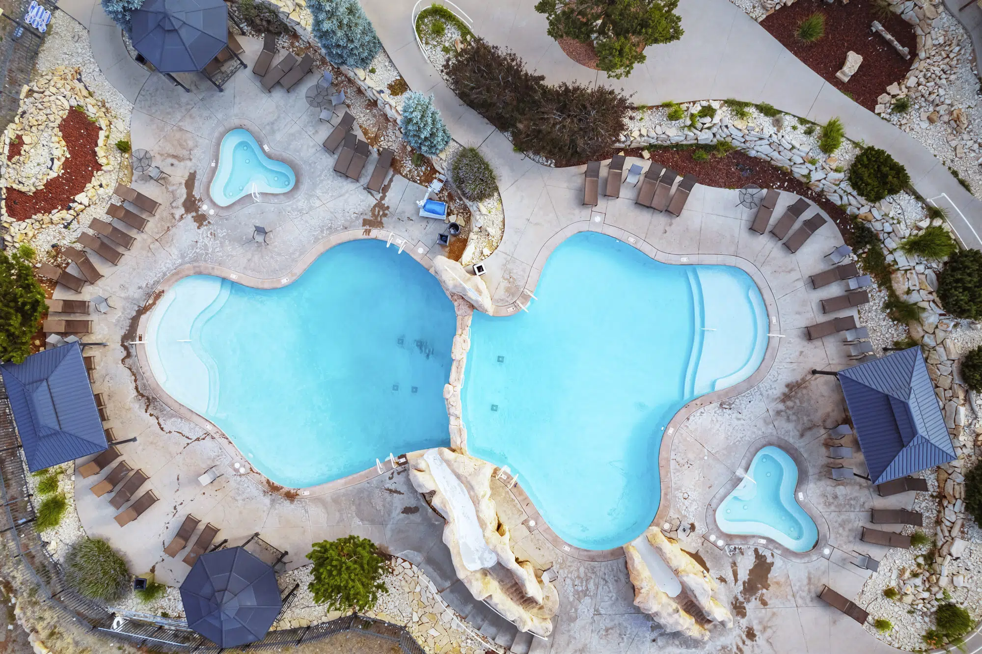 Aerial view of a resort-style pool complex with two main pools and surrounding lounge chairs.